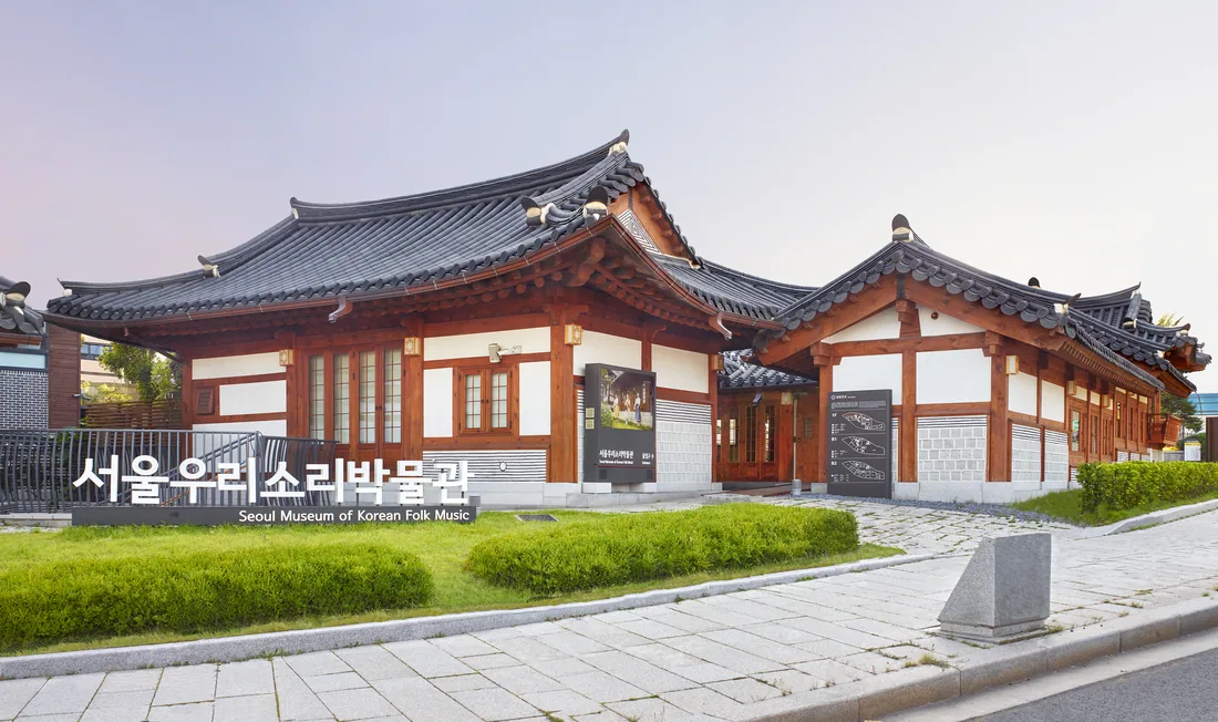 서울우리소리박물관 바깥 모습. 기와를 얹은 한옥 두 채가 나란히 서 있고 잔디밭 앞에 서울우리소리박물관이라고 새긴 표지석이 놓여 있다.