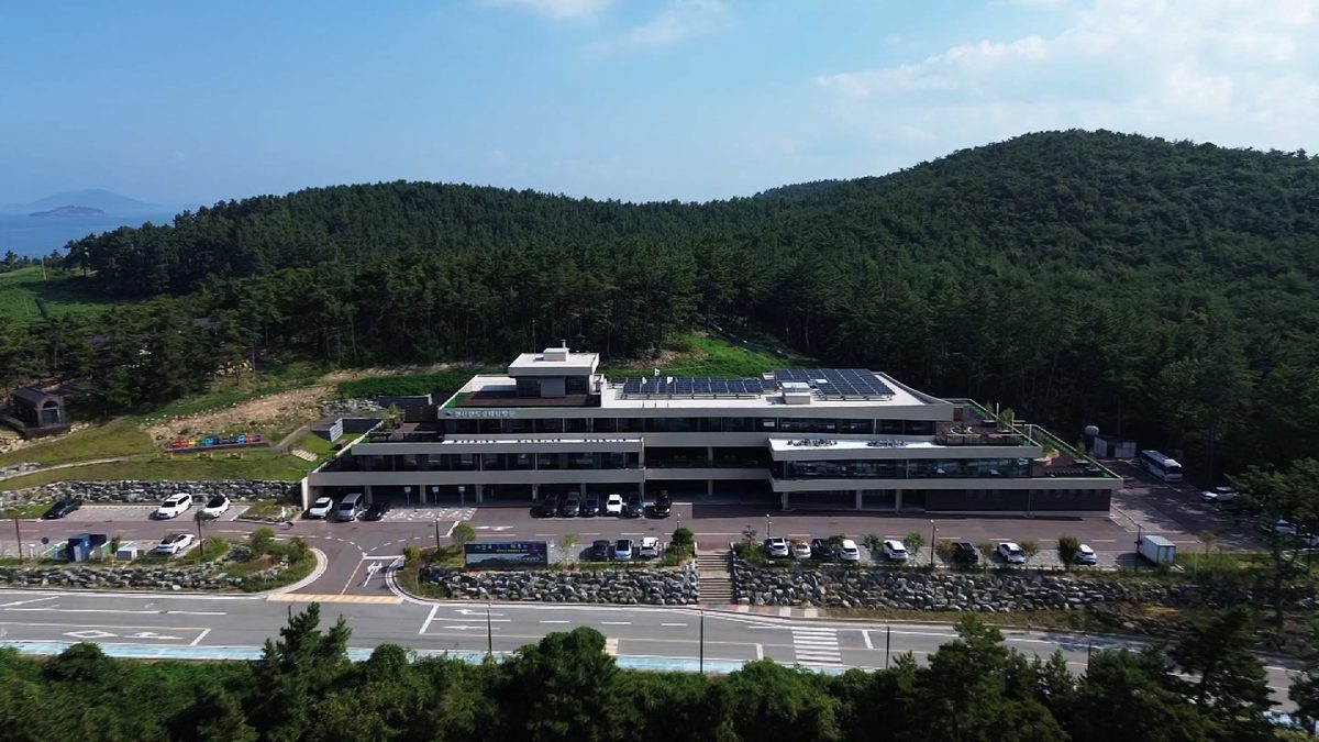 숲을 등지고 앉은 변산반도생태탐방원 건물과 앞마당 주차장