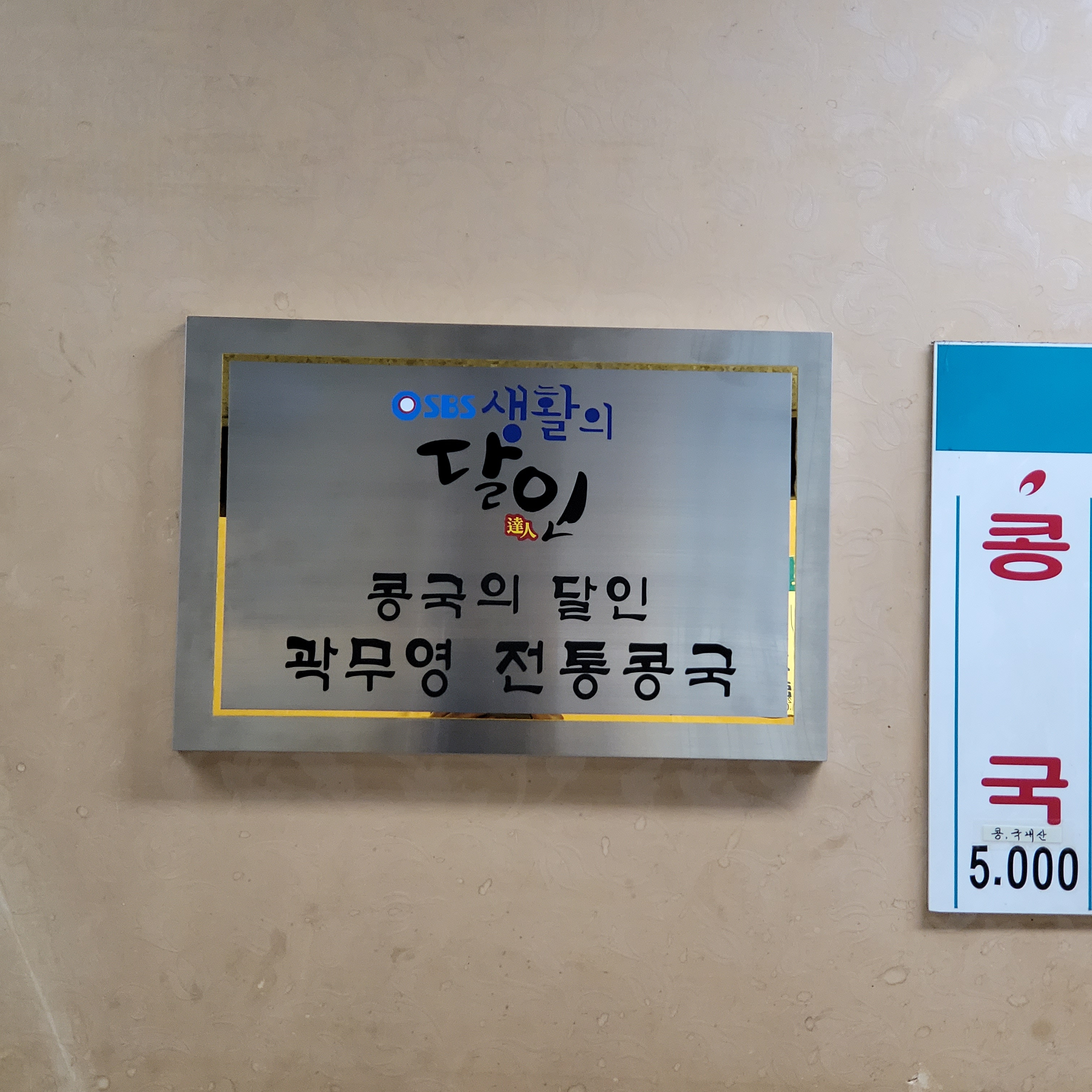 가게 벽에 걸린 SBS 생활의 달인 콩국의 달인 곽무영 전통콩국 명패, 옆에 콩국 5,000원 옛 값표