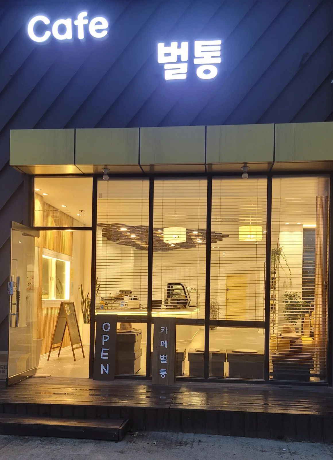 세종 조치원읍 세종로 2649 cafe벌통 외관. 밤에 Cafe 벌통 간판에 불이 들어와 있고 문 앞에 OPEN 입간판과 카페벌통이라고 세로로 쓴 배너가 서 있다.